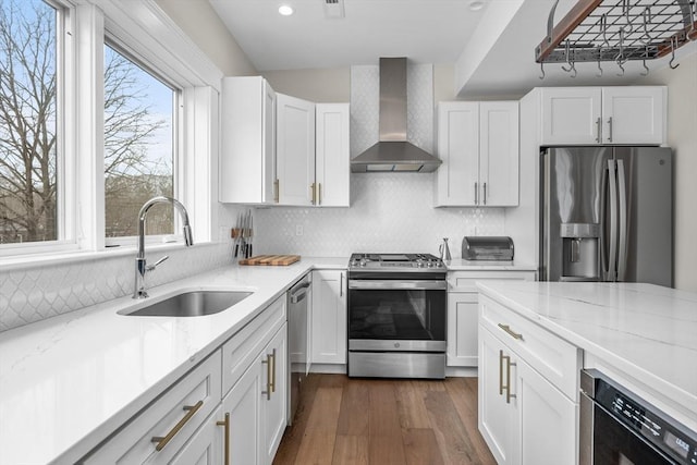 kitchen with beverage cooler, a sink, white cabinetry, wall chimney range hood, and appliances with stainless steel finishes