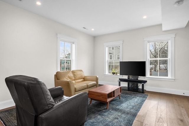 living area featuring a healthy amount of sunlight, hardwood / wood-style flooring, baseboards, and recessed lighting