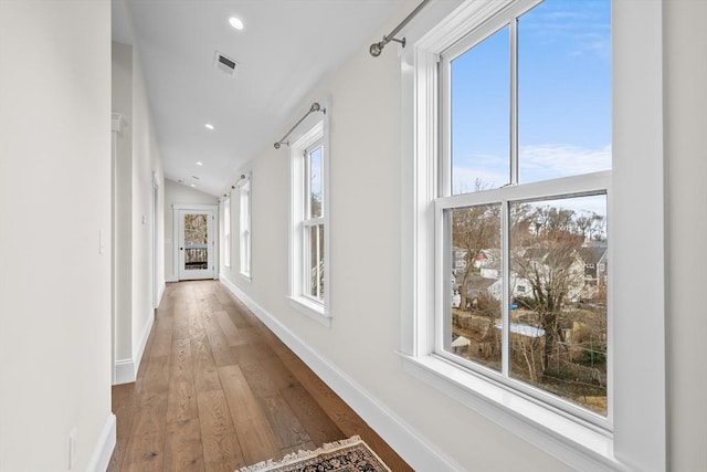 corridor featuring recessed lighting, wood-type flooring, visible vents, vaulted ceiling, and baseboards