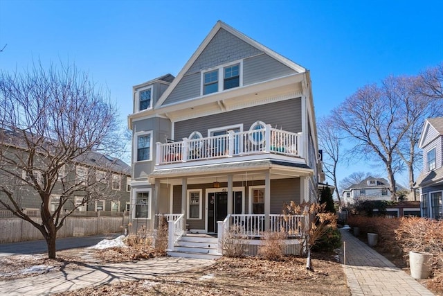 view of front of home featuring a balcony, covered porch, and fence