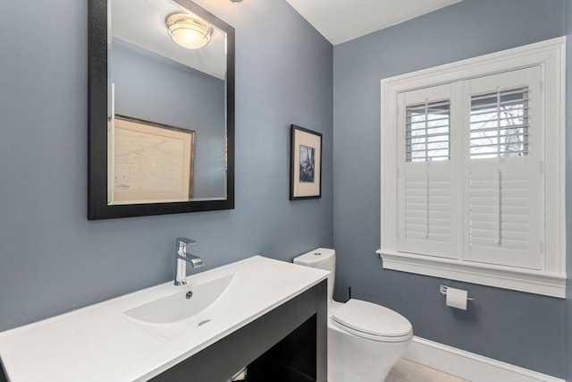 bathroom with toilet, vanity, and baseboards