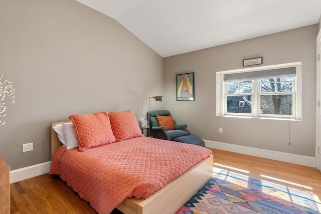 bedroom with baseboards, wood finished floors, and vaulted ceiling