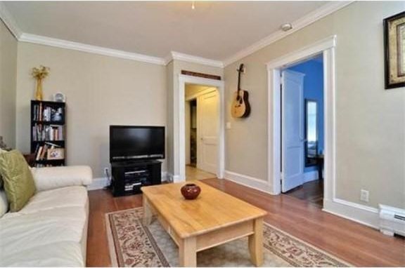living room featuring crown molding, baseboards, and wood finished floors