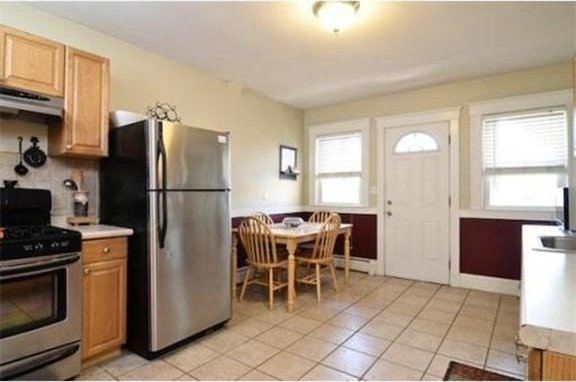 kitchen with light tile patterned floors, appliances with stainless steel finishes, under cabinet range hood, and a wealth of natural light