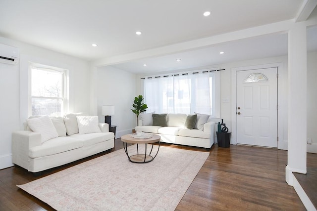 living room with dark wood-type flooring, beam ceiling, a healthy amount of sunlight, and a wall unit AC