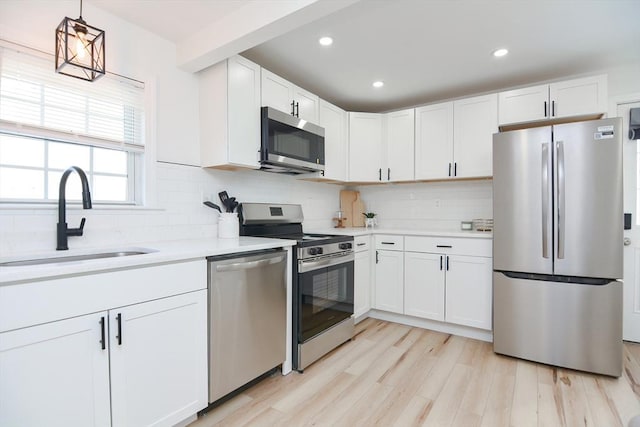 kitchen featuring white cabinets, appliances with stainless steel finishes, decorative light fixtures, decorative backsplash, and sink