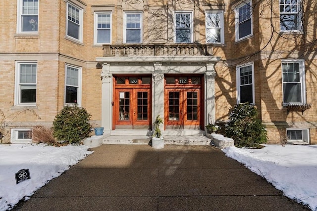 snow covered property entrance featuring french doors