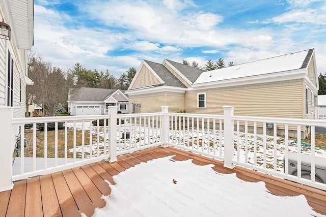 snow covered deck with an outbuilding and a garage