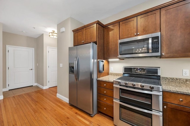 kitchen featuring light stone counters, stainless steel appliances, and light hardwood / wood-style floors