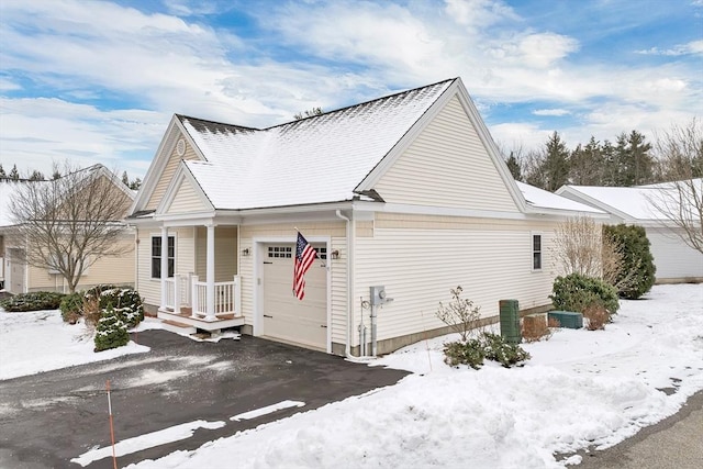 snow covered property with central AC unit and a garage