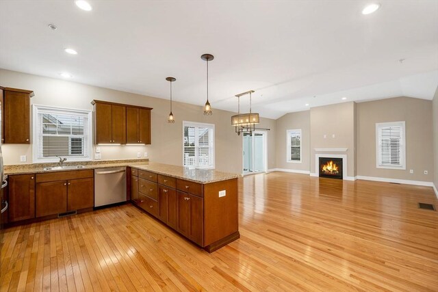 kitchen with stainless steel dishwasher, decorative light fixtures, light wood-type flooring, and sink