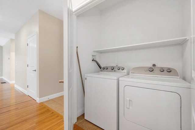 clothes washing area featuring washer and clothes dryer and hardwood / wood-style flooring