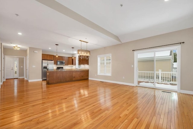 unfurnished living room featuring light hardwood / wood-style flooring and an inviting chandelier