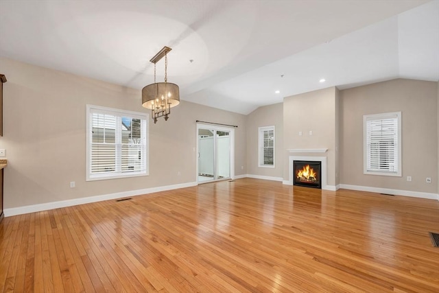 unfurnished living room featuring light wood-type flooring, lofted ceiling, and an inviting chandelier