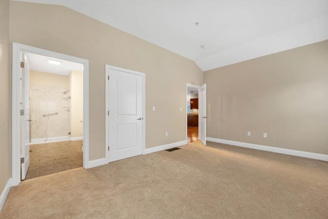 unfurnished bedroom with ensuite bathroom, light colored carpet, and lofted ceiling