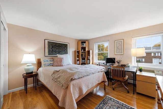 bedroom with light wood-type flooring and a baseboard heating unit