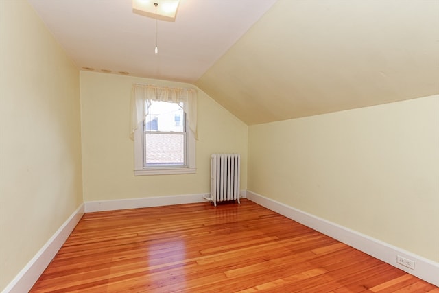 bonus room featuring light hardwood / wood-style flooring, lofted ceiling, and radiator