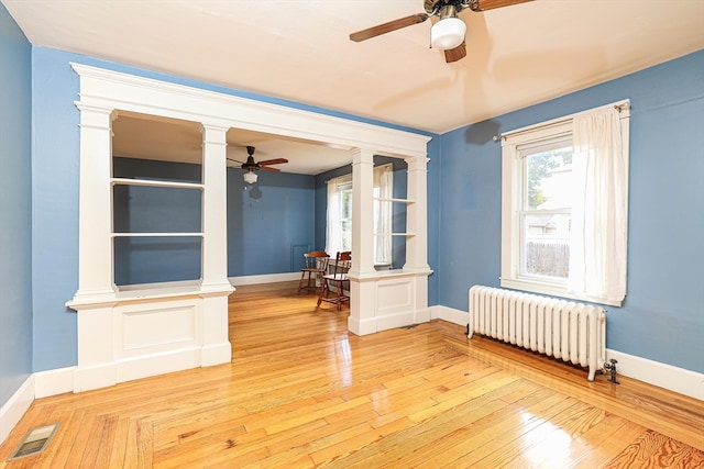 empty room featuring radiator heating unit, ceiling fan, and wood-type flooring