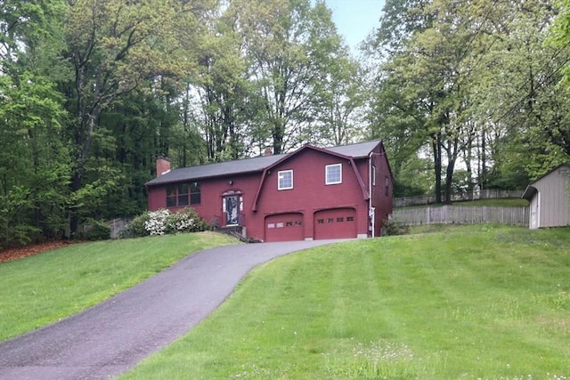 view of front of home featuring a gambrel roof, a garage, a chimney, driveway, and a front yard