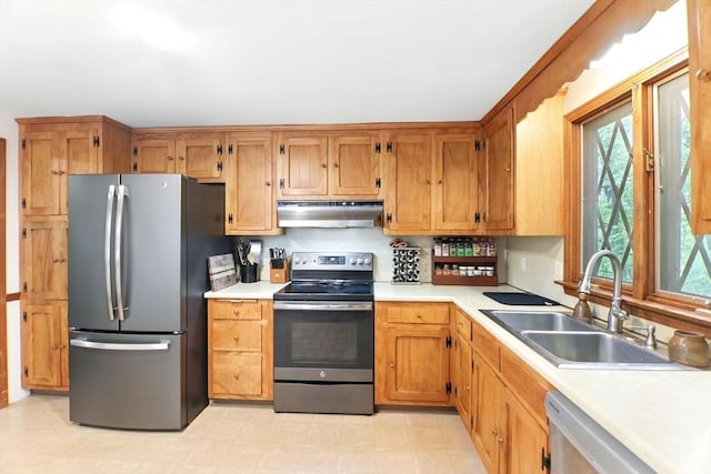kitchen featuring stainless steel appliances, under cabinet range hood, a sink, and light countertops