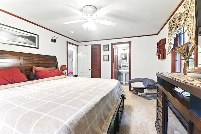 bedroom featuring carpet flooring, a sink, ensuite bathroom, ornamental molding, and a ceiling fan