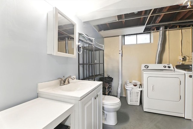 bathroom featuring washer and clothes dryer, a sink, finished concrete floors, and toilet