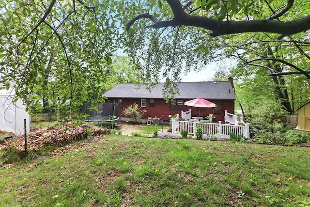 rear view of house with a trampoline and a wooden deck