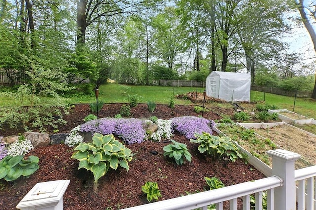 view of yard featuring a vegetable garden, a greenhouse, and an outdoor structure