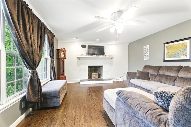 living area featuring a brick fireplace, baseboards, wood finished floors, ceiling fan, and ornamental molding