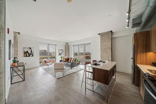 kitchen with stainless steel fridge, ornate columns, a kitchen island, range, and a breakfast bar area