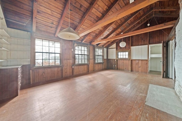 empty room featuring wood ceiling, wood walls, lofted ceiling with beams, and wood finished floors