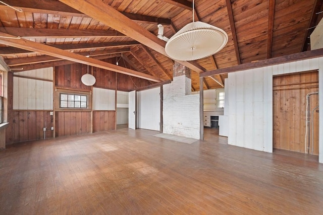 unfurnished living room with lofted ceiling with beams, dark wood-type flooring, wooden ceiling, and wooden walls