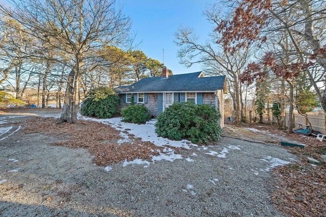 view of front of house with roof with shingles, fence, and a chimney