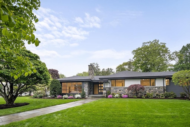 view of front of home with stone siding, a front lawn, and a chimney