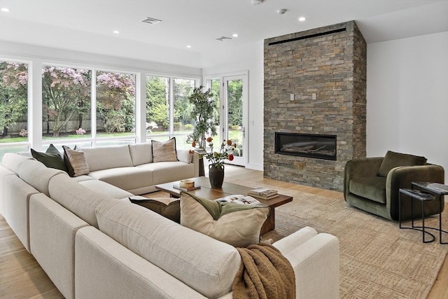 living area featuring light wood-style floors, a stone fireplace, and recessed lighting