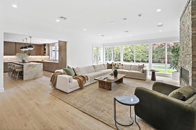 living room with light wood finished floors, recessed lighting, and a fireplace