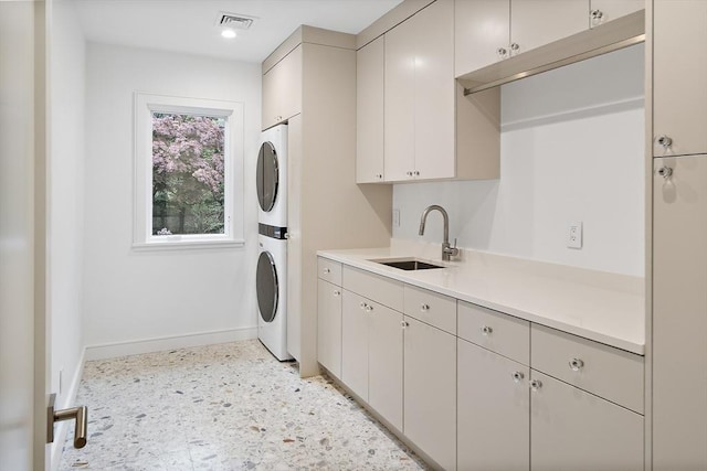washroom with stacked washer and clothes dryer, baseboards, and cabinet space