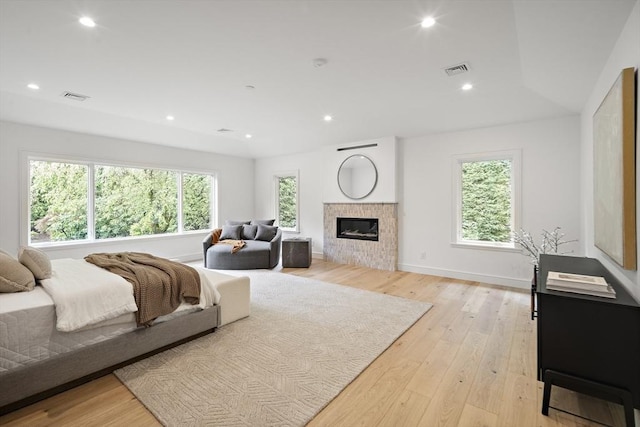 bedroom featuring light wood finished floors, a fireplace, recessed lighting, and baseboards