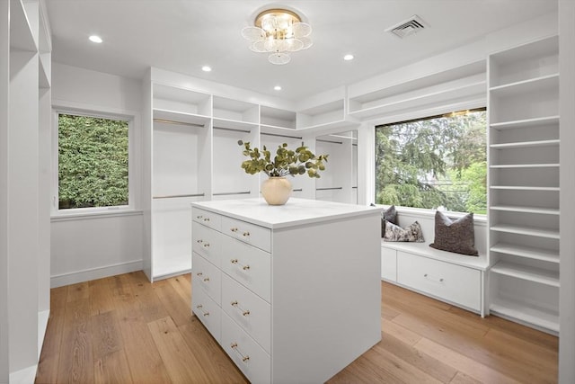 walk in closet featuring light wood-type flooring and a chandelier