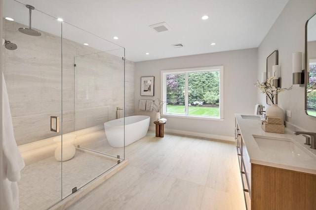 full bathroom featuring a shower stall, double vanity, recessed lighting, and a freestanding bath
