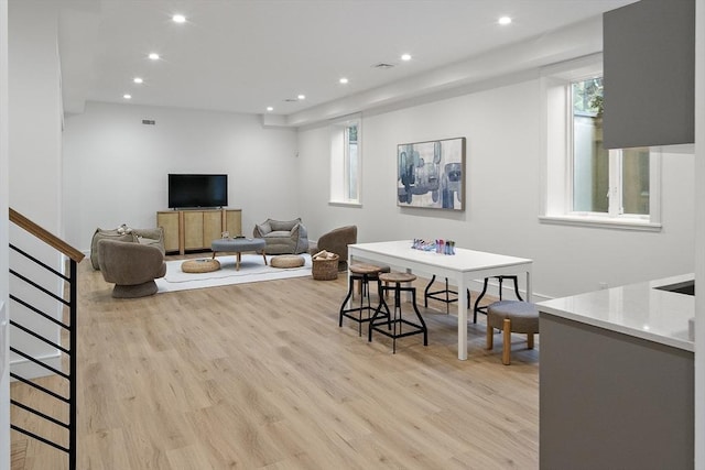living room featuring recessed lighting, light wood-style flooring, and stairs