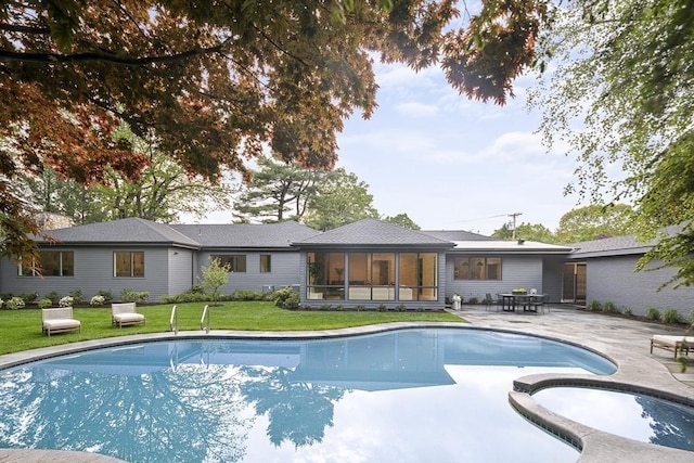 view of pool featuring a sunroom, a patio, a yard, and a pool with connected hot tub