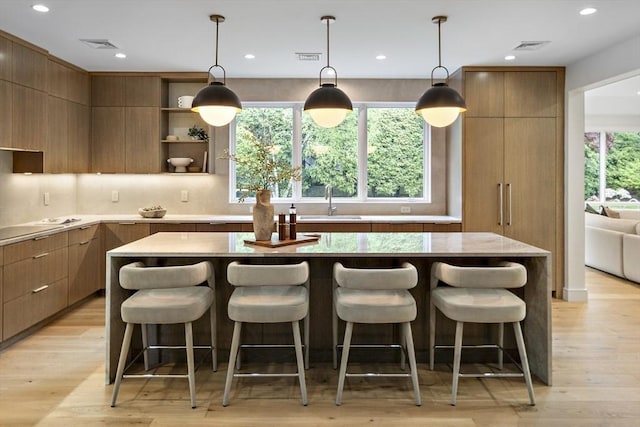 kitchen with modern cabinets, a sink, light wood-type flooring, a kitchen bar, and open shelves