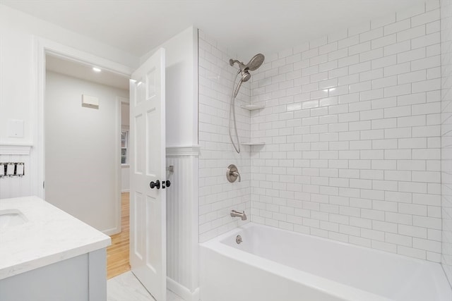 bathroom with vanity, hardwood / wood-style flooring, and tiled shower / bath