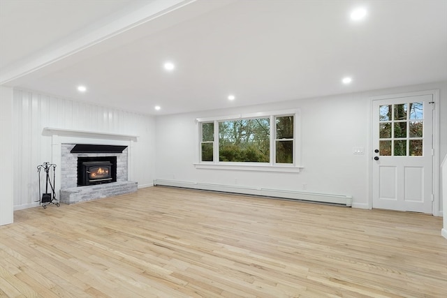 unfurnished living room with a fireplace, a healthy amount of sunlight, light wood-type flooring, and a baseboard heating unit