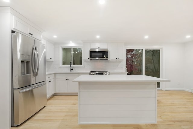 kitchen with a center island, appliances with stainless steel finishes, and light hardwood / wood-style flooring