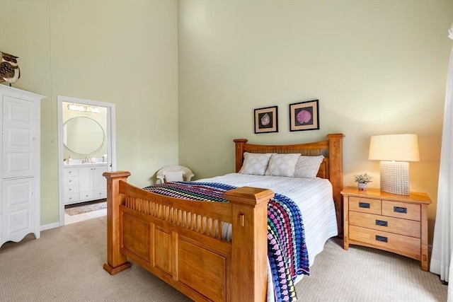 bedroom featuring light carpet, a high ceiling, and connected bathroom