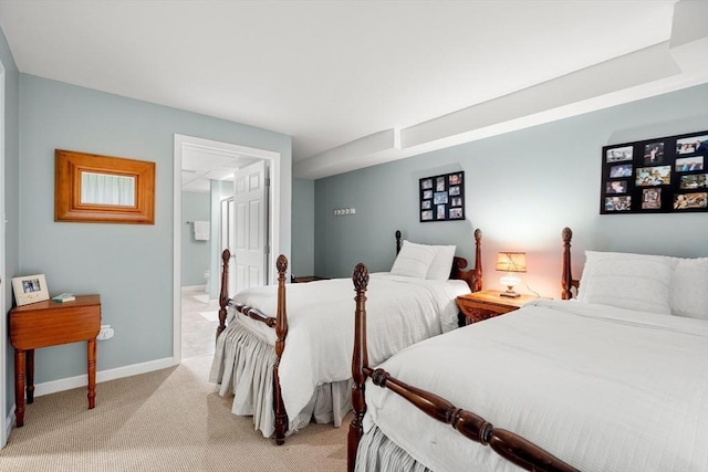 bedroom with ensuite bath, baseboards, and light colored carpet