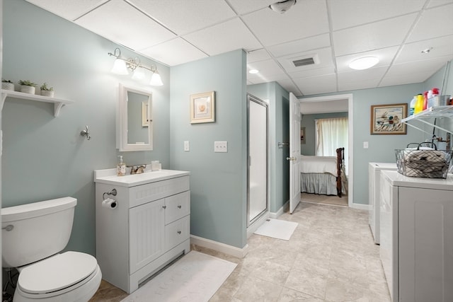 bathroom with toilet, walk in shower, a drop ceiling, vanity, and washer and dryer