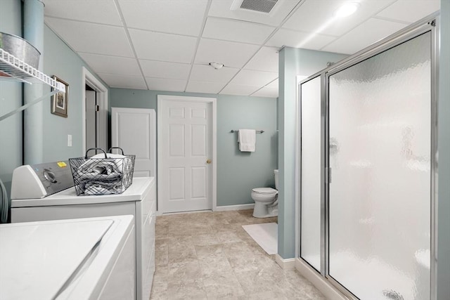 bathroom featuring visible vents, toilet, washing machine and dryer, a shower stall, and a drop ceiling